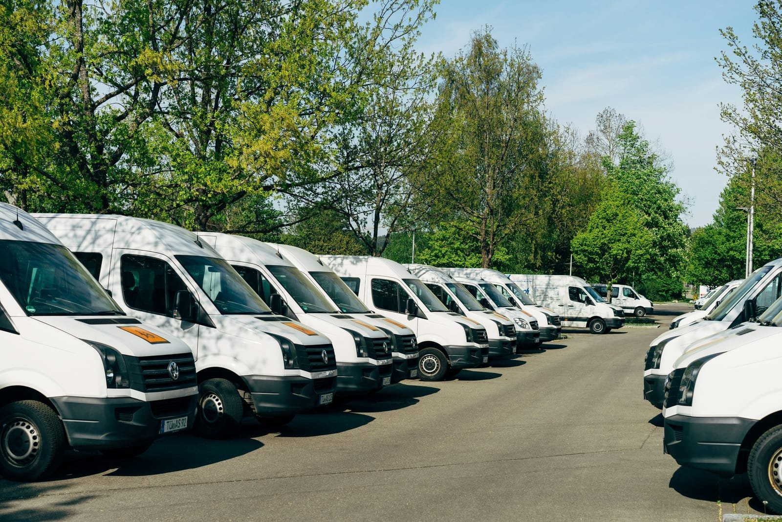 Row of white corporate fleet vans parked outdoors